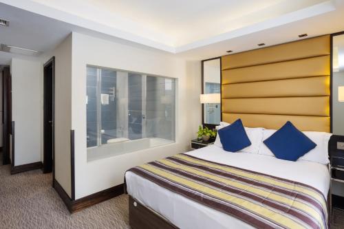 a hotel room with a large bed with blue pillows at Park Grand Mayfair in London