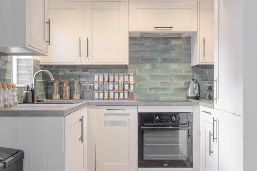 a white kitchen with white cabinets and an oven at 2 KING Beds Modern Refurb Flat - 10 min 2 London Bridge - Sleeps 6 in London