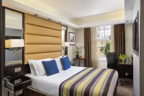 a hotel room with a bed and a desk at Park Grand Mayfair in London