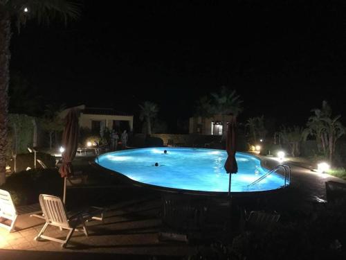 una grande piscina blu di notte con due sedie di Villetta tre delfini a Custonaci