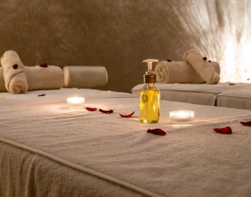 a bottle of oil and red rose petals on a bed at Riad Houma in Marrakech