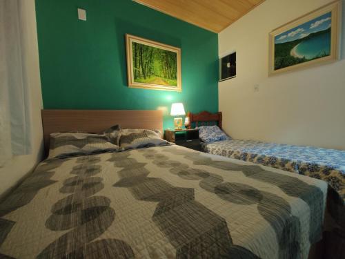 Un dormitorio con dos camas y una pared verde. en Casa 200 Arraial, en Arraial do Cabo