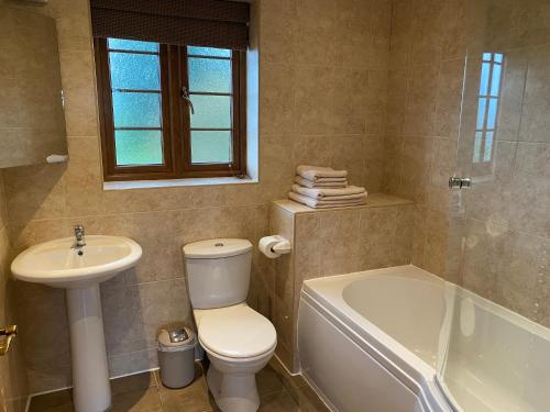 La salle de bains est pourvue de toilettes, d'un lavabo et d'une baignoire. dans l'établissement Red House Farm Cottages, à Beverley