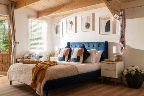 a bedroom with a blue bed with pillows at Copperbeech - Luxury Holiday with Private Hottub in Blandford Forum