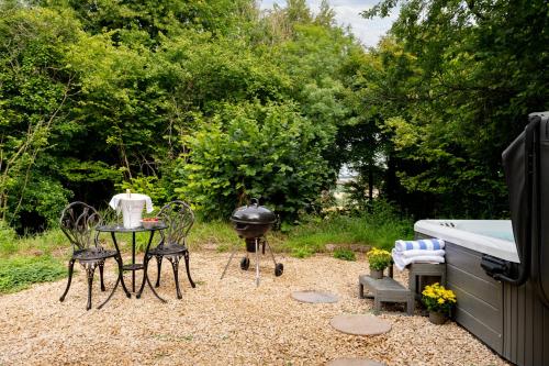 a backyard with a grill and a table and chairs at Copperbeech - Luxury Holiday with Private Hottub in Blandford Forum