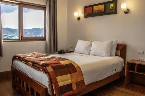 a bedroom with a bed and a large window at Amaru Colonial in Cusco