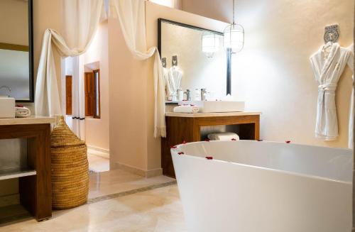 a bathroom with a large white tub and a sink at Riad Houma in Marrakesh