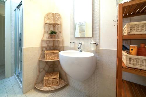 een badkamer met een witte wastafel en rieten manden bij VILLA INFINITY - Regarda Travel in Bardolino