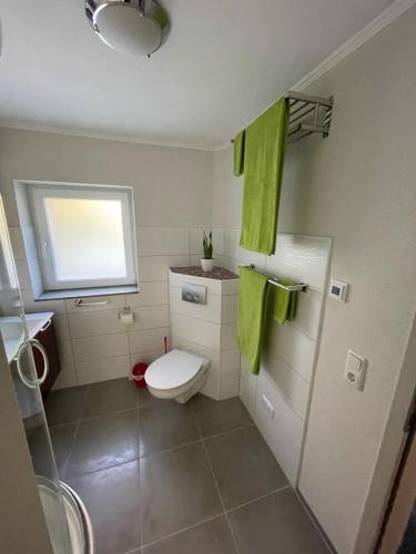 a bathroom with a toilet and a window and green towels at Haus am gelben Berg in Dittenheim