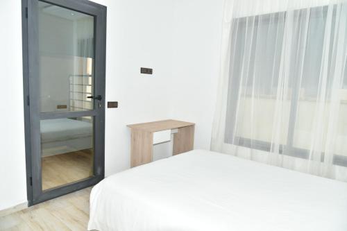 een slaapkamer met een wit bed en een spiegel bij BRAND NEW! 3 Bedroom Apartment in the Heart of Kenitra in Kenitra