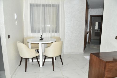 a white dining room with a table and chairs at Stylish 3-Bedroom Flat in Kenitra Center Ville with Parking & Comfort in Kenitra
