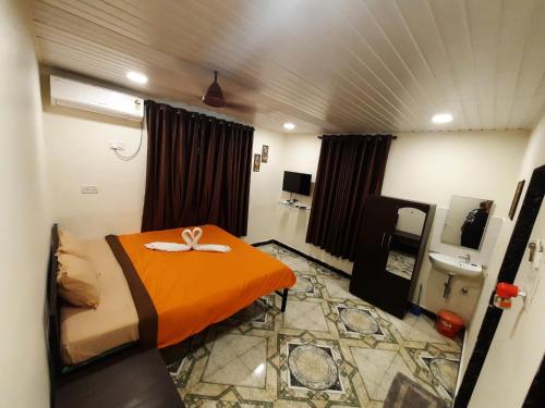een slaapkamer met een oranje bed en een wastafel bij Ashirvad cottage in Alībāg