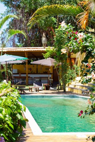 a resort with a swimming pool with tables and umbrellas at Villa Botanic Garden in Itacaré