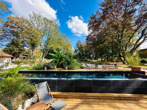 a swimming pool in a yard with a wooden deck at Les Chambres du parc 