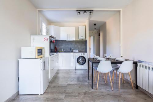 - une cuisine avec des appareils blancs, une table et des chaises dans l'établissement Superbe appartement T2 proche mer avec parking, à La Grande Motte
