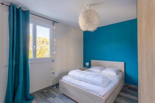 une chambre avec un lit avec un mur bleu dans l'établissement Superbe appartement T2 proche mer avec parking, à La Grande Motte