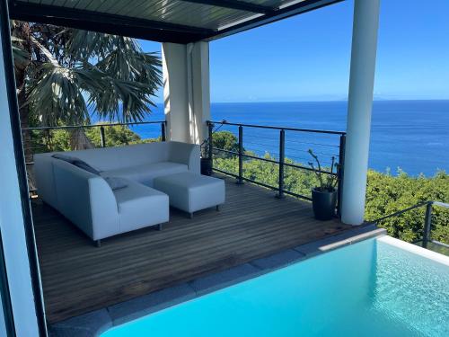 a balcony with a couch and a view of the ocean at Domaine entre ciel & mer Villa Dolce Vita in Deshaies