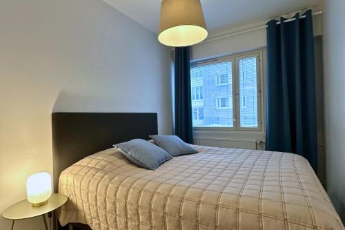 1 dormitorio con 1 cama con cortinas azules y ventana en City Apartment Haapaniemenkatu, en Kuopio