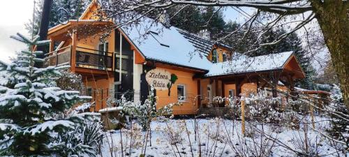 ein schneebedecktes Haus mit einem Schild davor in der Unterkunft Zielona Róża in Wambierzyce