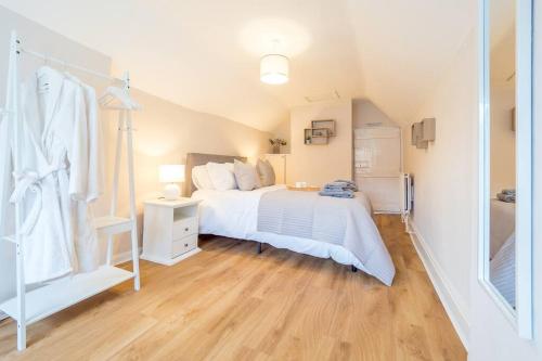 a bedroom with a white bed and a wooden floor at Hamlet's Nest in Stratford-upon-Avon