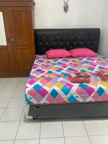 ein Bett mit einer bunten Bettdecke und Kissen darauf in der Unterkunft Wijaya homestay in Subang