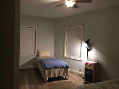 a bedroom with a bed with a blue blanket and two windows at CLARENDON,SUPRLOCATION,8ppl,PRIVATE,METRO,PARK in Arlington
