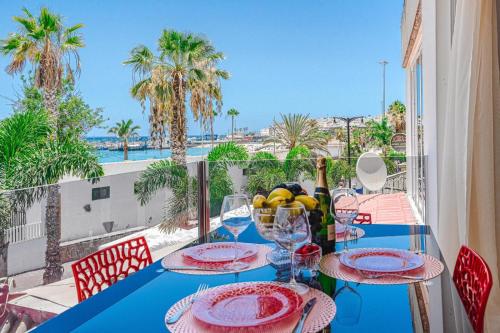 een blauwe tafel met borden en wijnglazen op een balkon bij Magaly in Los Cristianos