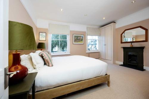 a bedroom with a large white bed and a fireplace at Veeve - Sunshine Joy in London