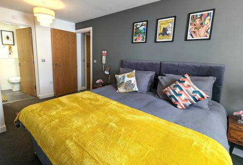 a bedroom with a blue bed with a yellow blanket at Beautiful Modern Coventry City Centre Apartment in Coventry