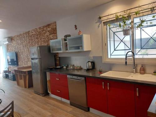 La cuisine est équipée de placards rouges et d'un réfrigérateur en acier inoxydable. dans l'établissement Maison entière Redessan, à Redessan