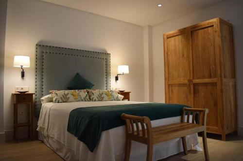 a bedroom with a bed with a bench and a wooden cabinet at Apartamentos Turísticos La Plaza in Chipiona