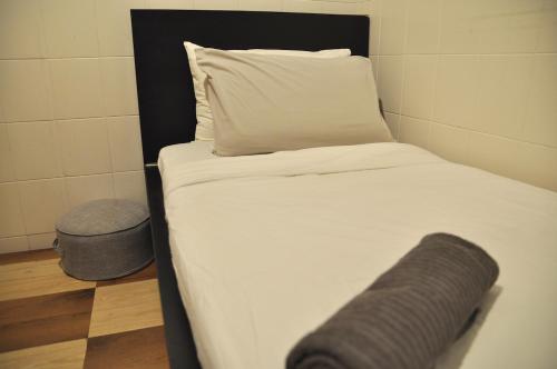 a made bed with a pillow and a trash can at GRAYHAUS Guest House in Petaling Jaya