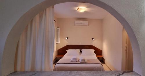 a bedroom with a bed and an archway with two shoes at Ammos Kalamitsi in Kalamitsi