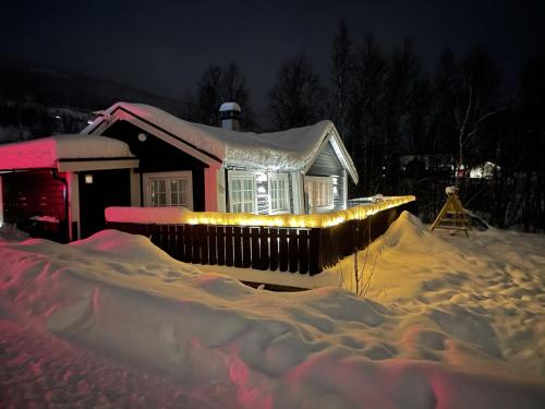 a house covered in snow with lights on it at Stugu - Koselig hytte med sentral beliggenhet 