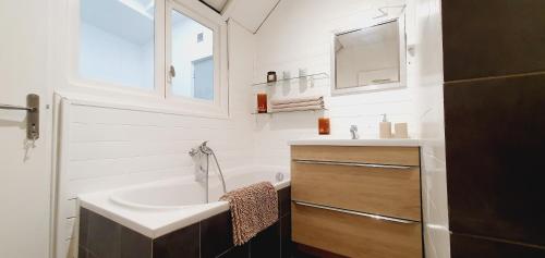ein weißes Badezimmer mit einem Waschbecken und einem Spiegel in der Unterkunft Le Delambre in Perpignan