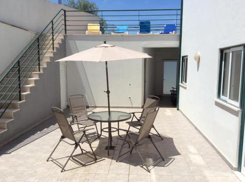 a table with chairs and an umbrella on a patio at Casa de Sandoeira in Rego da Murta