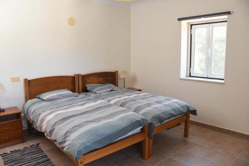 a bed in a white bedroom with a window at Casa de Sandoeira in Rego da Murta