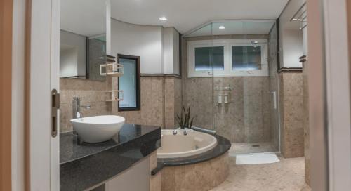 uma casa de banho com uma banheira, um lavatório e um chuveiro em Village Du Lac Hotel em Pomerode