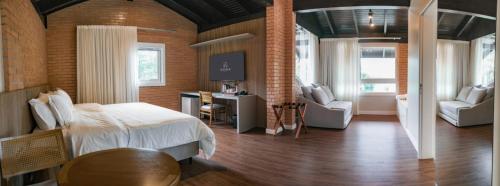 um quarto com uma cama e duas cadeiras e uma televisão em Village Du Lac Hotel em Pomerode