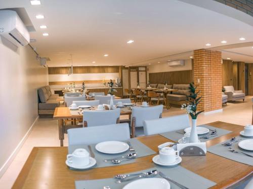 a dining room with white tables and white chairs at Village Du Lac Hotel in Pomerode