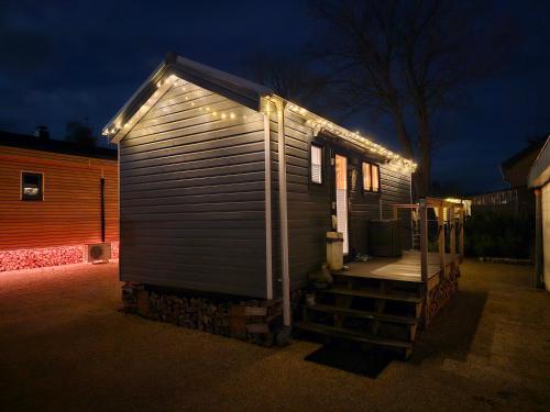 Une petite maison avec des lumières sur son côté dans l'établissement Tiny House Flensburg Luv, à Hornholz
