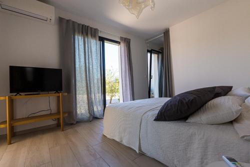 une chambre avec un lit et une télévision à écran plat dans l'établissement Villa MAYA, à Lecci