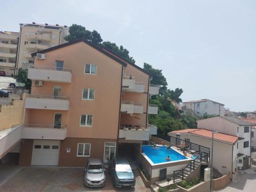 two cars parked in front of a building with a swimming pool at Apartments Vila Adrijana & Fitness Studio WOLF BV in Baška Voda
