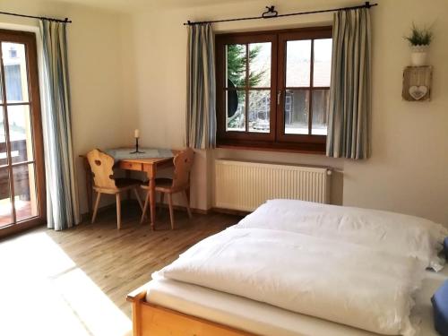 a bedroom with a bed and a desk and a table at Ferienwohnung zum Gimpei in Siegsdorf