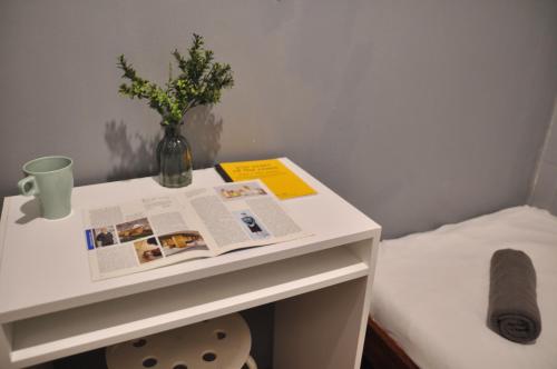 a table with a newspaper and a vase of flowers on it at GRAYHAUS Guest House in Petaling Jaya