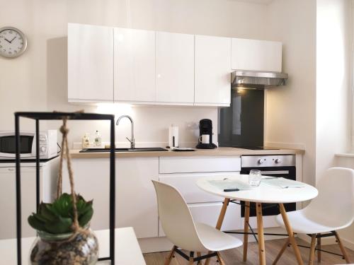 une cuisine avec des armoires blanches et une table et des chaises dans l'établissement Le Repère - Focalimmo (centre), à Foix