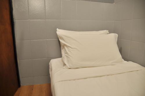 a white pillow sitting on top of a bed at GRAYHAUS Guest House in Petaling Jaya