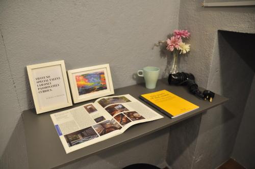 a table with two pictures and a magazine and a vase with flowers at GRAYHAUS Guest House in Petaling Jaya