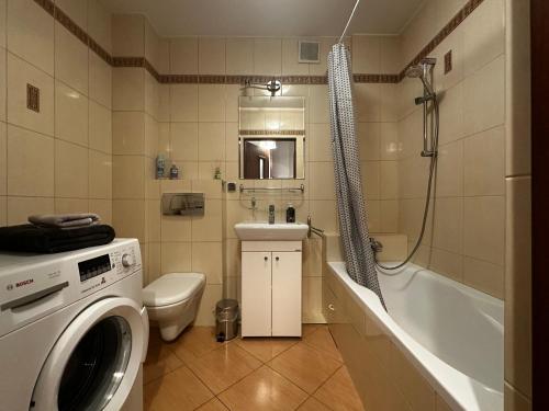 uma casa de banho com uma máquina de lavar roupa ao lado de um WC e uma banheira em Apartament Studio Kamienna street em Breslávia