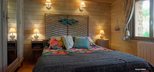 een slaapkamer met een groot bed met kleurrijke kussens bij RÉF 213 - RIANTEC Ty Maya Gîte sur propriété chaumière avec piscine partagée in Riantec